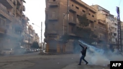 A tear-gas canister is thrown back toward security forces in Homs in late December.