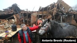 Farmer Tomislav Suknaić miluje konja ispred svog porušenog domaćinstva u selu Majske Poljane nakon raornog zemljotresa u Hrvatskoj. 30. decembar, 2020.