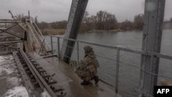 Український військовий стоїть на зруйнованому залізничному мосту через річку Оскіл під час розвідки біля лінії фронту в Куп’янську Харківської області, 15 грудня 2024 року 