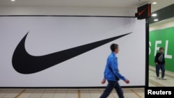 Njerëzit duke kaluar pranë një dyqani të mbyllur të Nike-s në Shën Petersburg, Rusi. 