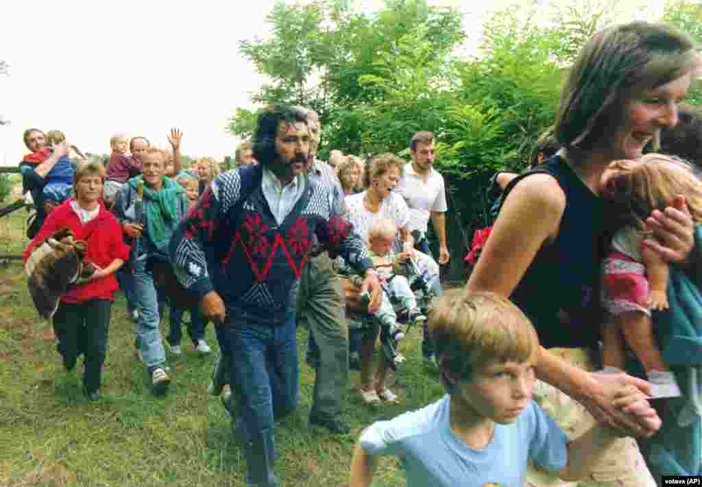 Est-germani care fug din Ungaria în Austria pe 19 august 1989, în timpul „Picnicului paneuropean”. Mii de est-germani au început să fugă din Ungaria în Austria, dintre care circa 600 într-o singură zi, în timpul unui protest de tip festival, cunoscut sub numele de Picnicul paneuropean, la granița dintre Austria și Ungaria. Exodul, care a fost în scurt timp permis în mod deschis de Ungaria, a stârnit proteste furibunde din partea Germaniei de Est, care a susținut că cetățenii săi au fost „seduși și plătiți să emigreze... pentru a defăima statul nostru”.