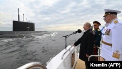 Ռուսաստանի նախագահ Վլադիմիր Պուտինը, պաշտպանության նախարար Սերգեյ Շոյգուն և Ռազմածովային նավատորմի հրամանատար, ծովակալ Նիկոլայ Եվմենովը Ռազմածովային ուժերի օրվան նվիրված շքերթի ժամանակ, հուլիս, 2021թ.
