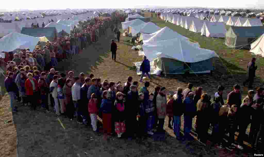 Qindra refugjatë shqiptarë presin për të marrë ushqime në një kamp refugjatësh në afërsi të Shkupit, 8 prill 1999. David Silverman/Reuters. 