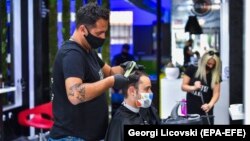 Një floktar ka vendosur maskë në fytyrë, teksa ia prenë flokët një personi. Shkup, 30 prill, 2020.