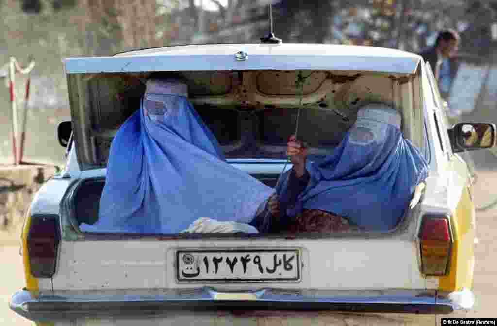 Gra afgane me burka duke u vozitur në bagazhin e një automjeti. (Çarikar, 18 shkurt 2003)