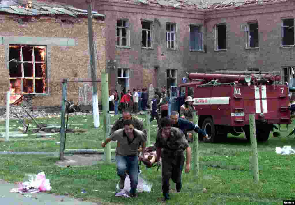 Vullnetarët bartin një civil të lënduar, ndërsa ushtarët sulmojnë shkollën më 3 shtator, ditën e tretë të krizës së pengjeve. Një numër dëshmitarësh thanë se panë zjarr dhe tanke në shkollë. 