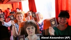 Fotografie făcută într-un autobuz din Donețk în 27 iunie 2020. Călătorii în drum spre secțiile de votare din Rusia își arată pașapoartele rusești. 