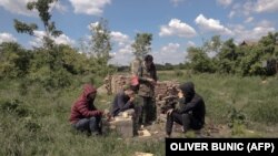 СРБИЈА - Група мигранти се одмараат на поле во близина на српското село Мајдан, близу границите на Унгарија и Романија. 21 мај 2021 година