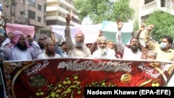 People hold a banner reading in Arabic, "I will sacrifice my parents for the Prophet's honor" during a protest in Hyderabad on July 30 to support the man who killed a man accused of blasphemy.