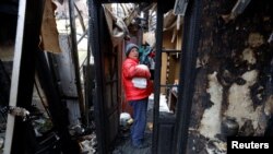 Талкаланган үйдүн урандыларынын арасында турган аял. Украина.