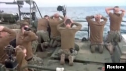 U.S. sailors are pictured on a boat with their hands on their heads at an unknown location in this still image taken from video taken on January 12-13.