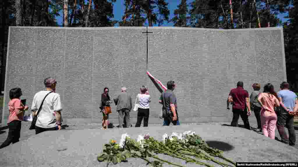 Біля польського військового цвинтаря. Тут спочивають близько 2 тисяч поляків, розстріляних 1940 року загонами НКВС за наказом Сталіна. Меморіал у Биківні – це четвертий «катинський цвинтар», після кладовищ у Катинському лісі, Мєдному (Росія) та Харкові-П’ятихатках. Весною 1940 року жертвами НКВС загалом стали понад 22 тисячі польських полонених, захоплених у неволю після наступу СРСР на Польщу. Ця трагедія ввійшла до історії як Катинський злочин