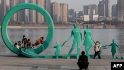 5 ianuarie, Wuhan - Oameni care fac poze lângă o statuie recent renovată, ce reprezintă o familie cu trei copii, în parcul Hankou (AFP/CHINA OUT)