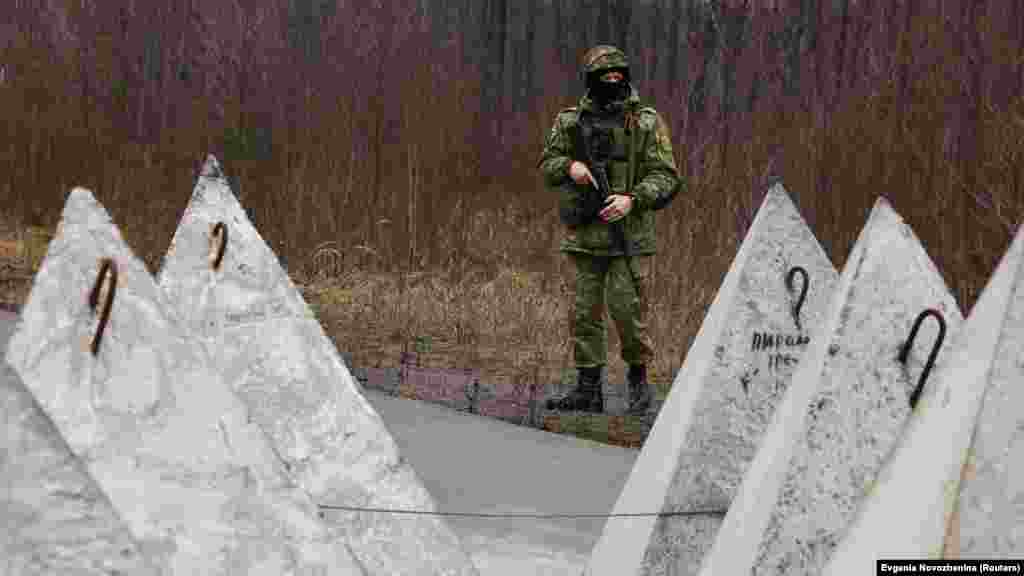 Një ushtar bjellorus duke patrulluar kufirin me Ukrainën. Fotografia shfaq fortifikata kundërtank, të njohura si &quot;dhëmbët e dragoit&quot;.