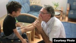 بوسه نوری‌زاد بر پای کودکی که در خانواده‌ای بهایی متولد شده و پدر و مادرش زندانی هستند.