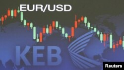 South Korea -- A currency dealer walks past a screen displaying the exchange rate between the dollar and the euro at the headquarters of the Exchange Bank in Seoul, 10May2010