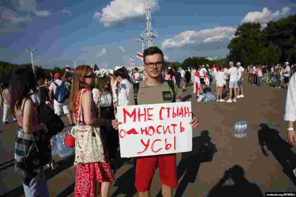 Еден човек има транспарент кој вели: „Се срамам да носам мустаќи“, осврнувајќи се врз мустаќите на лицето што ги носи Лукашенко.