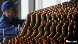 Un angajat lucrează la o linie de îmbuteliere a berii la o fabrică de bere Carlsberg din Krasnoyarsk. (fotografie de arhivă)
