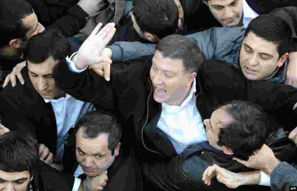 Tbilisi, 8 fevral 2013. Milli kitabxana qarşısında Saakashvili əleyhidarlarının etiraz aksiyası. Tbilsinin meri Gigi Ugulava (ortada) qəzəbli kütlənin ortasında
