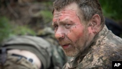Un soldat ucrainean primește primul ajutor pe un drum în apropiere de Bahmut, la 11 mai.