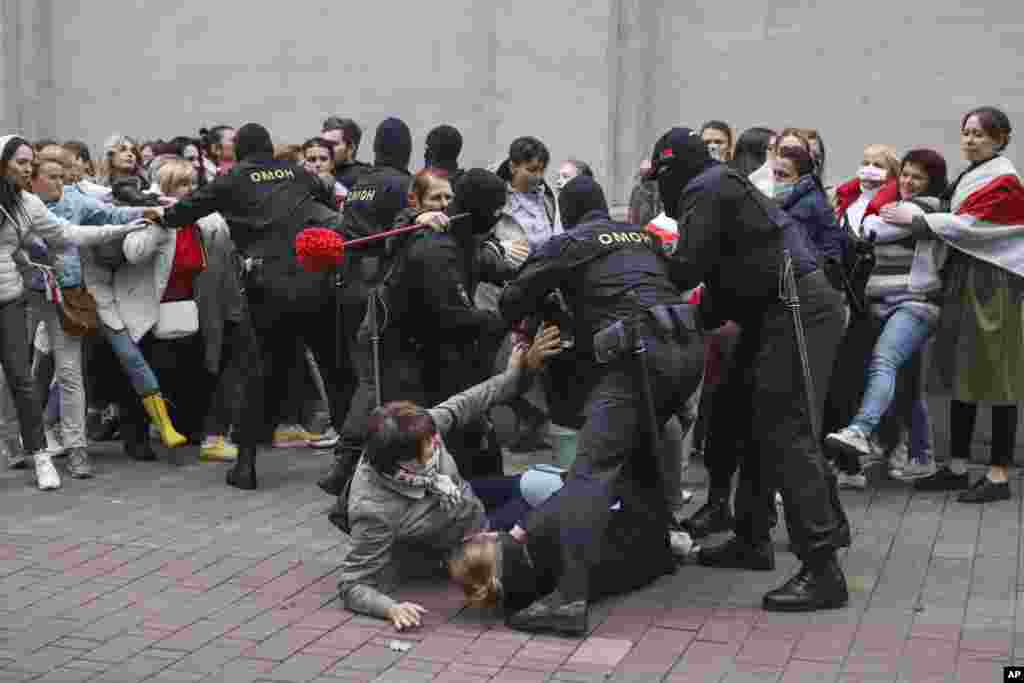 Ofițerii de poliție arestează câteva protestatare. 
