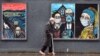 Egy idős férfi híres műalkotások maszkos graffitije előtt sétál el Glasgow-ban, 2020. szeptember 2-án 
