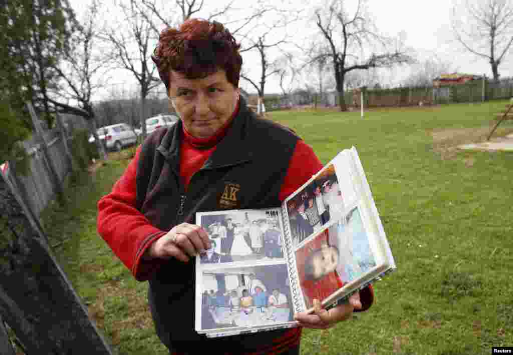 Meštanka sela pokazuje fotografije stanovnika sela Velika Ivanča, 9. april 2013. Foto: REUTERS / Marko Đurica