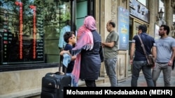 Disa iranianë duke qëndruar pran një këmbimoreje në Teheran. 11 prill, 2018
