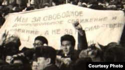Участники демонстрации на площади Брежнева, ныне площадь Республики, держат плакат с надписью «Мы за свободное добровольное слияние и сближение...». Алматы, декабрь 1986 года. (Фотокопия из центрального государственного архива Алматы.) 
