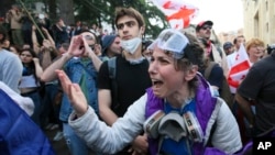 Egy tüntető vitatkozik a rendőrökkel a „külföldiügynök-törvény” elleni ellenzéki tüntetésen a tbiliszi parlament épülete előtt 2024. május 28-án