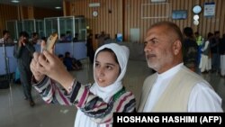 Afghan teenager Fatema Qaderyan takes a photograph with her father at Herat International Airport before heading to the United States last month for a robotics competition.