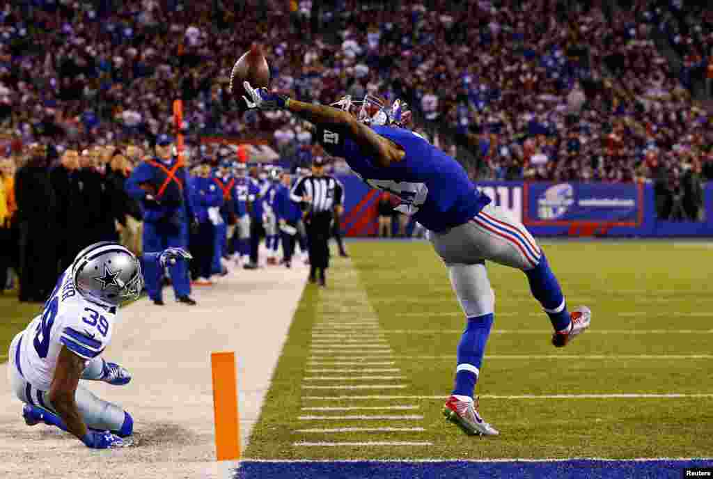 Игрок клуба американской Национальной футбольной лиги New York Giants Оделл Бекхэм зарабатывает тачдаун в матче против Dallas Cowboys. Фотография Эла Белло, первое место в категории "Спорт. Одиночные снимки". 