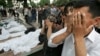 Люди молятся около тел жертв расстрела в Андижане. 14 мая 2005 года.