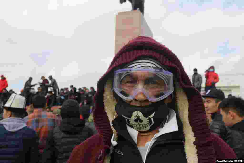 Мужчина в маске и очках на площади «Ала-Тоо», где идет митинг.