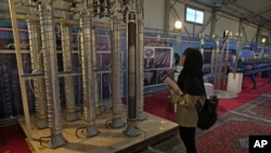Diáklány egy centrifuga előtt az Irán nukleáris eredményeit bemutató kiállításon Teheránban 2023. február 8-án