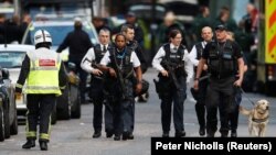 Armed police officers walk outside London's Borough Market where a terror attack on June 3 left seven people dead.
