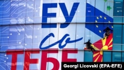 Punëtorët vendosin posterin e ri në zyrat e Bashkimit Evropian në Shkup ku shkruan “BE-ja me ju”. Shtator, 2021. 