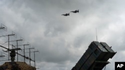 Винищувачі F-16 ЗСУ пролітають над ЗРК «Патріот» у невідомому місці в Україні. 2024 рік