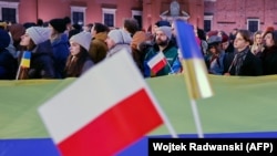 Люди з польськими та українськими прапорами слухають промову президента України Зеленського та президента Польщі Дуди у дворі Королівського замку. Варшава, 5 квітня 2023 року