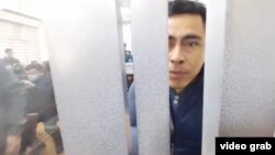 Bloger Otabek Sattoriy Jinoyat ishlari bo‘yicha Muzrabot tuman sudi zalidagi sudlanuvchilar uchun ajratilgan bo‘lmada. 2021, 11 - mart. Effect.uz sayti e’lon qilgan videodan kadr.