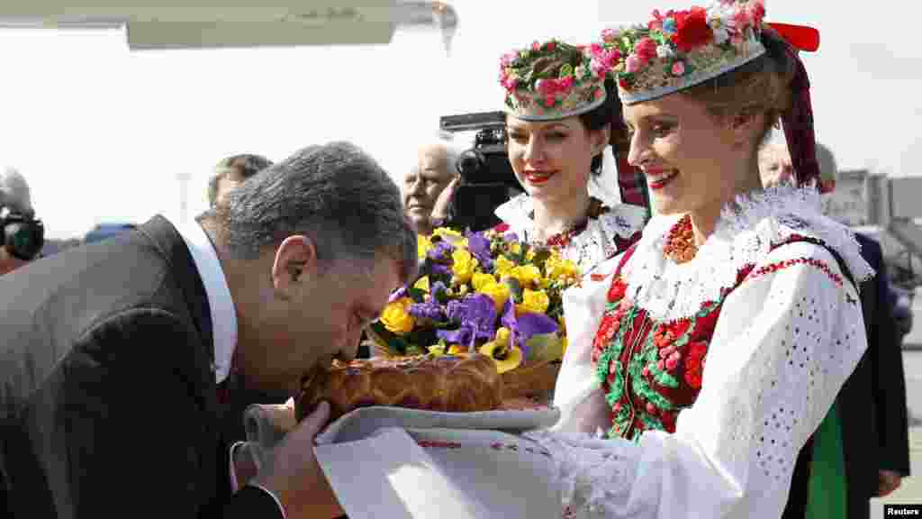 Украина президенті Петр Порошенко өзін әуежайда қарсы алғанда ежелгі дәстүр бойынша ұсынылған нан-тұздан дәм татып тұр. Минск, 26 тамыз 2014 жыл.
