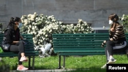 Două prietene stau de vorbă într-un parc din Milano