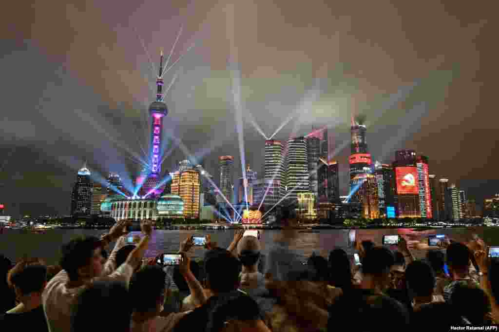 Spectatorii urmăresc un spectacol de lumini pe faimoasa promenadă Bund din Shanghai pe 1 iulie, când sărbătorile la nivel național se apropie de sfârșit. 