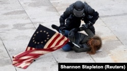 Un polițist arestează o demonstrantă pro-Trump în timpul violențelor declanșate de suporterii președintelui perdant la clădirea Capitoliului, Washington, 6 ianuarie 2021