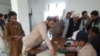 د سدې د ووټونو په مرکز کې یو کس تر خپلې رایې کارولو مخکې پر فارم ګوته لګوي. 