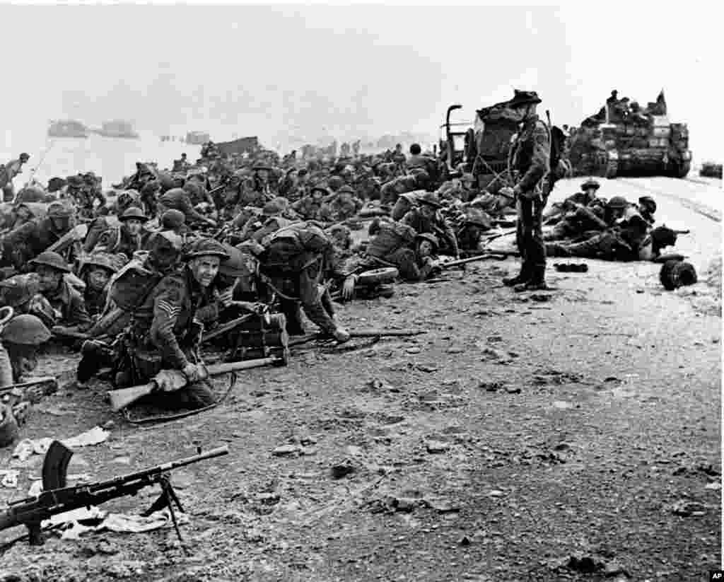 După aterizare, trupele britanice așteaptă semnalul pentru a avansa. Fotografie realizată la începutul operațiunilor de aterizare aliate din Normandia, Franța, 6 iunie 1944