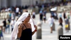 Një grua duke ecur në rrugë gjatë një vale të të nxehtit në Vatikan në korrik të vitit 2023. 