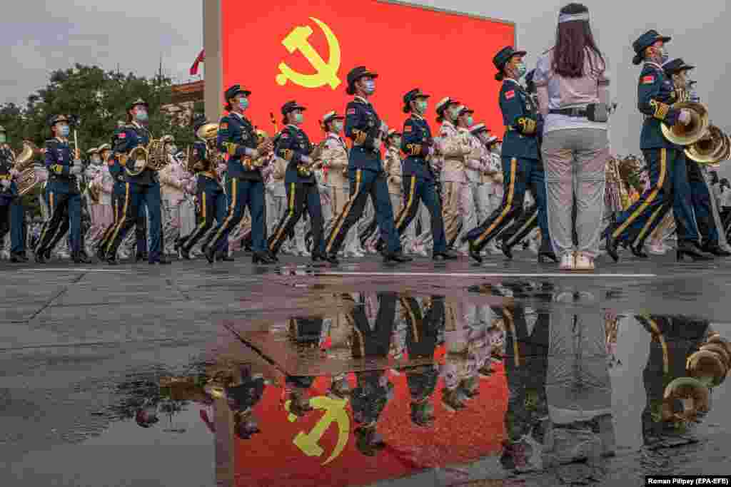 Membrii armatei chineze mărșăluiesc pe lângă un ecran pe care este expus drapelul comunist chinez în timpul sărbătorilor aniversare din Piața Tiananmen. Comuniștii chinezi s-au inspirat din teoria marxistă și de la revoluționarii bolșevici ruși atunci când și-au format partidul în iulie 1921.