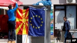 Nje djalë duke varur flamurin e Maqedonisë së Veriut dhe atë të BE-së.