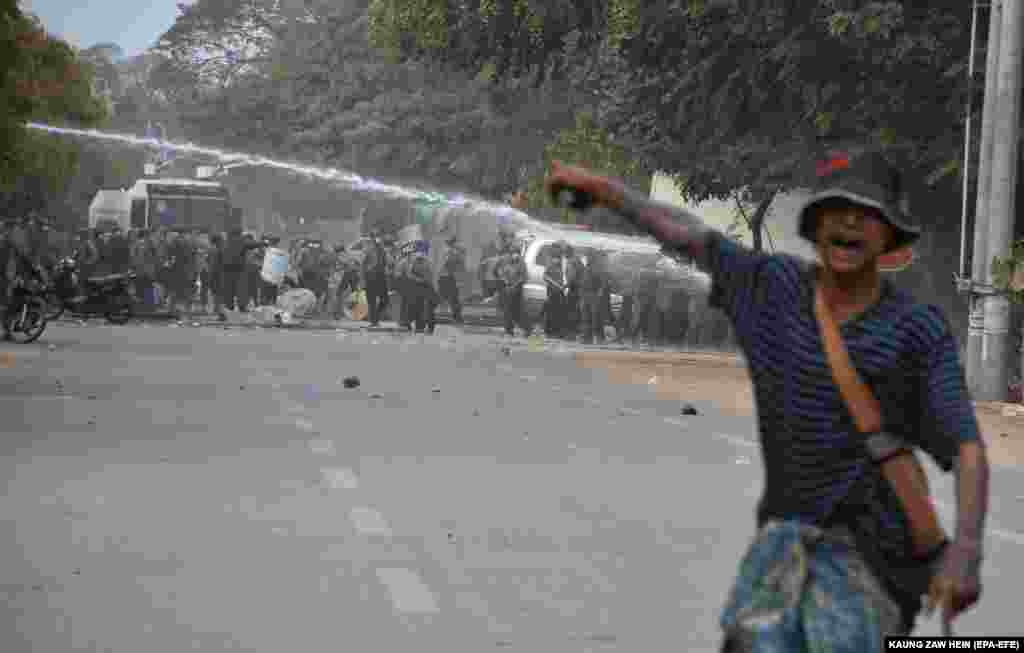 Un protestatar arată cu degetul spre tunurile de apă folosite de poliția în timpul unui protest împotriva loviturii de stat militare. Mandalay, Myanmar, 20 februarie 2021. (Foto: Kaung ZAW HEIN / EPA-EFE )